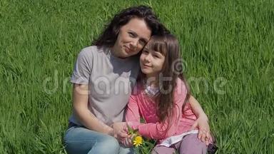 妈妈在绿色的草坪上拥抱女儿。 <strong>公园里</strong>有个孩子的女人<strong>坐在</strong>草地上。 夏天的家庭